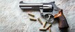 © Steveandfriend - Close-up of a silver revolver with bullets, showcasing polished craftsmanship and detailed design on a textured surface.