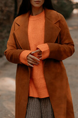 Wall Mural - Fashion details of brown coat and knitted orange sweater on female figure, warm autumn seasonal clothing