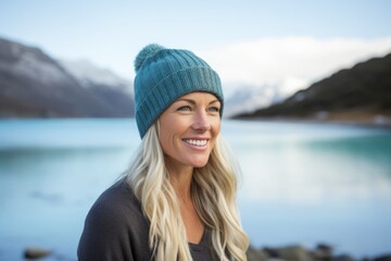 Poster - Portrait of a blissful woman in her 40s sporting a trendy beanie while standing against beautiful lagoon background