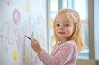 © Alexandra - Young girl is expressing her creativity by drawing on a whiteboard with a colorful marker