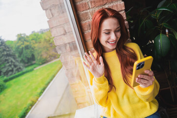 Wall Mural - Portrait of nice young girl smart phone make selfie arm wave hi wear yellow sweater loft interior flat indoors