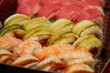 © Александр Ланевский - Philadelphia sushi rolls with avocado and salmon in dark set box and in warm light blurred background, blurred sushi in soft warm light, showing the texture and detail of the ingredients.