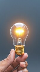 Poster - Hand Holding a Light Bulb With a Glowing Filament.