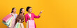 © Prostock-studio - Three Excited Ladies Buyers Shopping Holding Shopper Bags Pointing Finger Showing Something Standing On Yellow Studio Background.