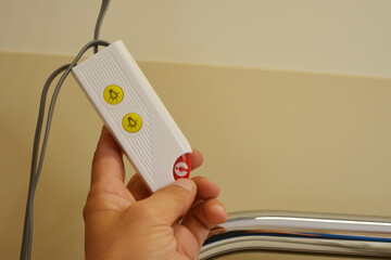 A hand holds an emergency call button to get help in the hospital