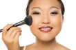 © vladimirfloyd - Closeup portrait of a young Asian woman applying blush.