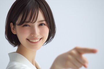 a cheerful japanese woman in her early 20s smiles and points at the viewer with one hand, dressed in