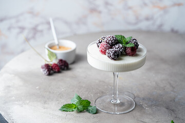 Wall Mural - Delicious italian dessert panna cotta with iced berries and mint on light background.