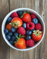 Bowl of fresh mixed berries on rustic wooden background