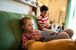 © Marko Geber - Kids reading books on the couch at home