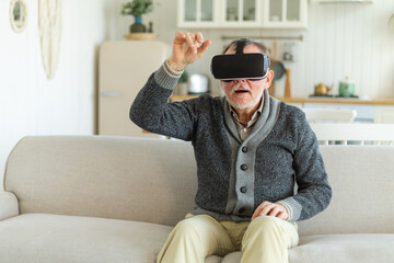 Wall Mural - Excited mature senior man wearing using virtual reality metaverse VR glasses headset at home. Grandfather touching air during VR experience on virtual reality helmet. Simulation hi-tech videogame