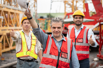 Wall Mural - Portrait mature caucasian engineer man worker  with team and spare crane background