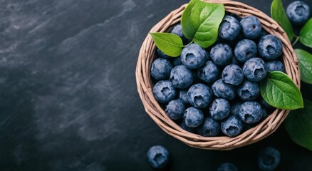 Wall Mural - Fresh blueberries in a wicker basket on a dark textured surface with green leaves