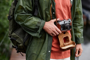 Closeup of unrecognizable male tourist holding vintage photo camera while travelling in nature, copy space