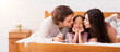 © Prostock-studio - Parents Love. Portrait Of Loving Mother And Father Giving A Kiss To Their Little Daughter From Both Sides While Lying Together In Bed