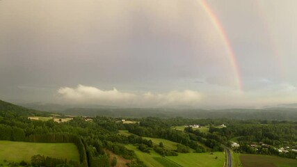 Wall Mural - magical rainbow over a misty countryside landscape. enchanted forests, rolling green fields, distant