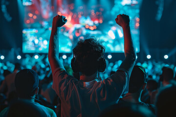 A man is standing in a crowd of people, holding his hands up in the air