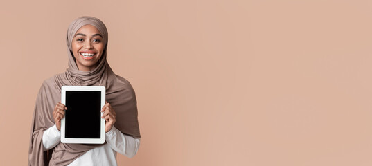 Poster - Smiling afro woman in headscarf demonstrating digital tablet with black screen for mockup, posing over yellow background, empty space