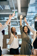 © SensSai/peopleimages.com - Happy business people, high five and stretching with team for winning, success or mission at office. Young, group or excited employees with smile or reaching up for unity, synergy or celebration