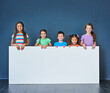 © Koegelenberg Coop/peopleimages.com - Children, happy and portrait for placard, advertising and marketing with mockup space in studio. People, smile and face on blue background for banner, branding and presentation with logo information
