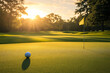 © AspctStyle - Golf ball near hole on sunlit green at sunrise, serene morning on a pristine golf course