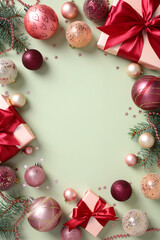 Wall Mural - Christmas frame border of pine branches, shiny baubles, and gifts with red ribbons on a pastel green background