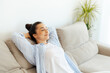 © Kateryna - Relaxation after workday. Happy calm indian or arabian woman resting on comfortable couch at home alone in living room, closed her eyes daydreaming or taking day nap, enjoying leisure time, smiling