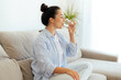© Kateryna - Beautiful happy calm arabian or indian brunette woman in casual wear is drinking a glass cup of clean water in the morning, while sits on sofa in living room at home, leads healthy life style concept