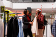 © DC Studio - Sales assistant presenting clothes to woman, recommending trendy model for christmas dinner formal attire. Fashionable asian client looking for new clothing line in mall store, xmas sales on holiday.