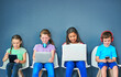 © Koegelenberg Coop/peopleimages.com - Study, technology and education with children in studio for online classes, connection and remote learning. Digital portal, virtual school and webinar with students on wall background for mockup