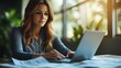 © Aqeel - an Businesswoman working attentively in front of a laptop, reviewing documents and planning strategies in a focused manner.