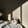 © Nattawee - A modern alarm clock with a sleek design resting on a bedside table, casting a soft shadow on the surface, against a