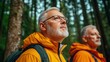© Shisanupong - Elderly man in an orange jacket and glasses hiking in a dense forest, looking upwards with a thoughtful expression, another man in the background...