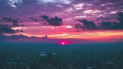 Poster - A breathtaking sunset casts a colorful glow over the city, with the sun dipping below the horizon and buildings creating striking silhouettes.