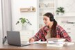 © New Africa - Student in headphones studying at wooden table indoors