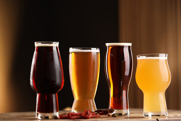 Wall Mural - Glasses with different types of beer and snacks on wooden table against color background