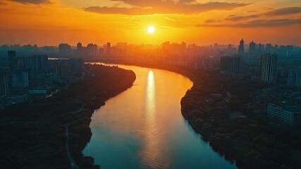 Aufkleber - The sun sets behind a city skyline, casting golden light on a winding river, creating a serene and colorful reflection in the water at dusk.