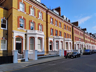 Poster - Street of yellow brick townhouses with red trim around windows