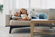 © SHOTPRIME STUDIO - Mother and daughter peacefully napping on a cozy couch surrounded by a laptop and lush green plants in a tranquil room