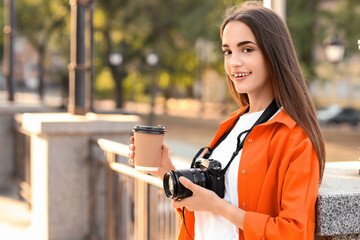 Wall Mural - Young female photographer with modern camera and coffee in park