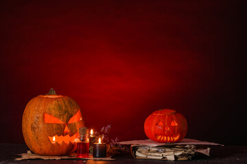 Sticker - Halloween composition with jack-o-lantern, candles, bottle of poison and spell book on table near red wall