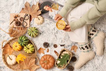 Sticker - Female legs in warm socks with autumn leaves, pumpkins and cup of tea on white plaid as background