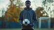 © zainab - A young athlete stands confidently on a soccer field at dusk, holding a ball and preparing for practice with determination and focus