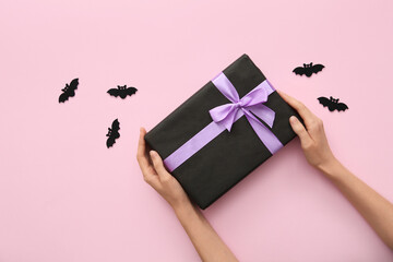 Canvas Print - Female hands with Halloween gift and bats on lilac background. Top view