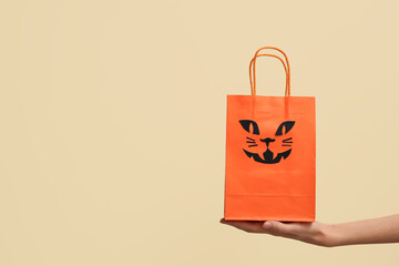 Sticker - Female hand with Halloween shopping bag on beige background