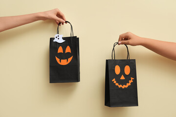 Wall Mural - Female hands with Halloween shopping bags on beige background