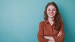 © zainab - A young woman smiles confidently with crossed arms in front of a turquoise background during daytime