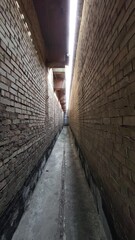 Wall Mural - a long, narrow brick tunnel between two buildings, into which light enters from a crack above. dolly