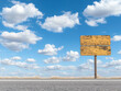 © Hew Pallot - wooden signpost on empty road with blue sky