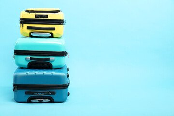 Sticker - Stack of different suitcases on light blue background, space for text